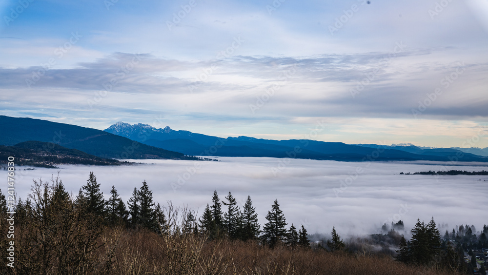 Fototapeta premium Low-lying clouds over Fraser Valley, BC, Canada with alpine mountains in silhouette on horizon.