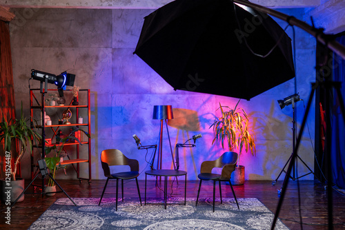 Podcast studio setup featuring microphone, chairs, and colorful lighting for interviews and broadcasts