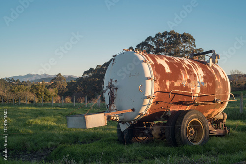 Depósito de agua oxidado en parcela de pastos photo