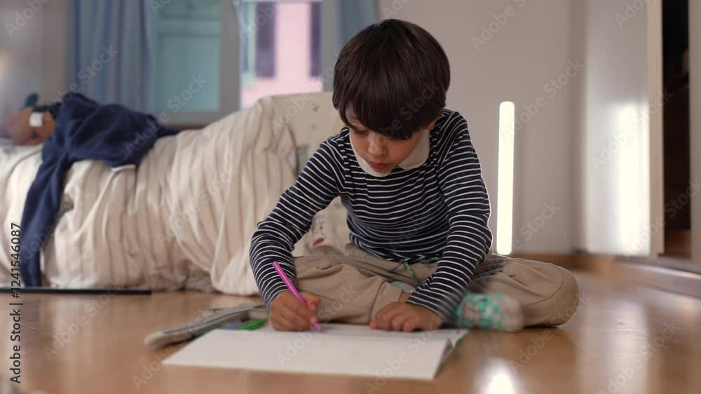 Young boy sitting cross-legged on floor, deeply focused while drawing with pink pencil, expressing concentration, creativity, and engagement in artistic or learning activity Young boy sitting cross-legged on floor, deeply focused while drawing with pink pencil, expressing concentration, creativity, and engagement in artistic or learning activity