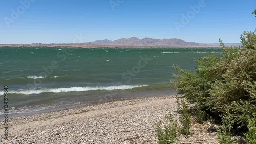 Powerful wind gusts whip Lake Havasu's surface, generating choppy waves and foamy white caps, showcasing nature's raw energy in this popular Arizona waterway.