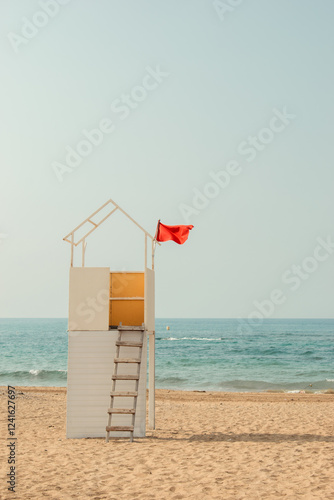 A white wooden tower on an empty sandy beach by the sea. Lifeguard station.