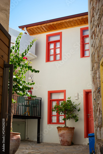 The facade of a house with red windows in a European city. The alley between the houses