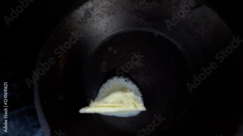 Cinematic footage of butter melting in an old frying pan before cooking. Cooking process