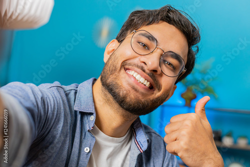 POV view of Indian young man blogger taking selfie on smartphone communicating video call online with subscribers recording stories for social media. Happy Arabian guy holds mobile phone on hand photo