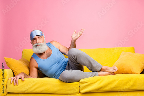 Fényképezés Senior man relaxing on a sofa in a bright colorful room, wearing casual homey cl