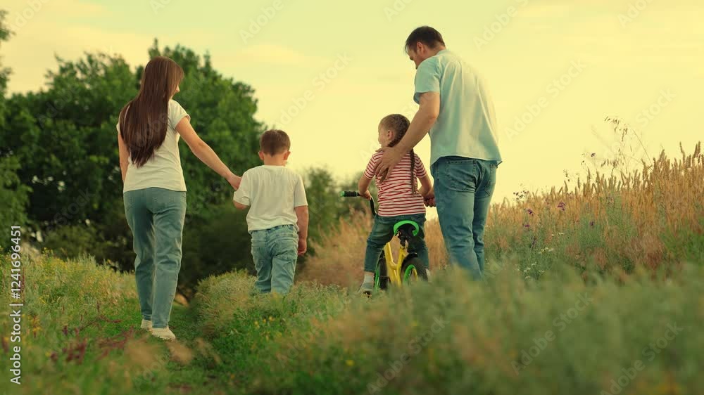 Dad, Mom teaches children to ride bike, sunset. Family, mother, child son parental support. Father teaches his child daughter to keep balance while sitting on bicycle. Childhood dream of riding bike. Dad, Mom teaches children to ride bike, sunset. Family, mother, child son parental support. Father teaches his child daughter to keep balance while sitting on bicycle. Childhood dream of riding bike.