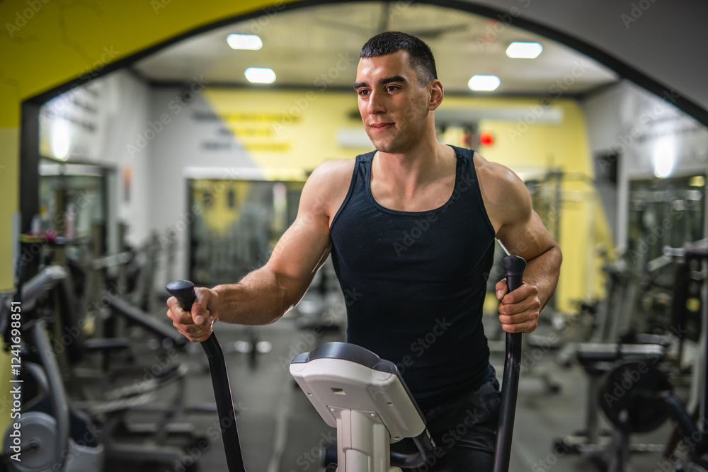 young caucasian muscular man use elliptical machine at gym young caucasian muscular man use elliptical machine at gym