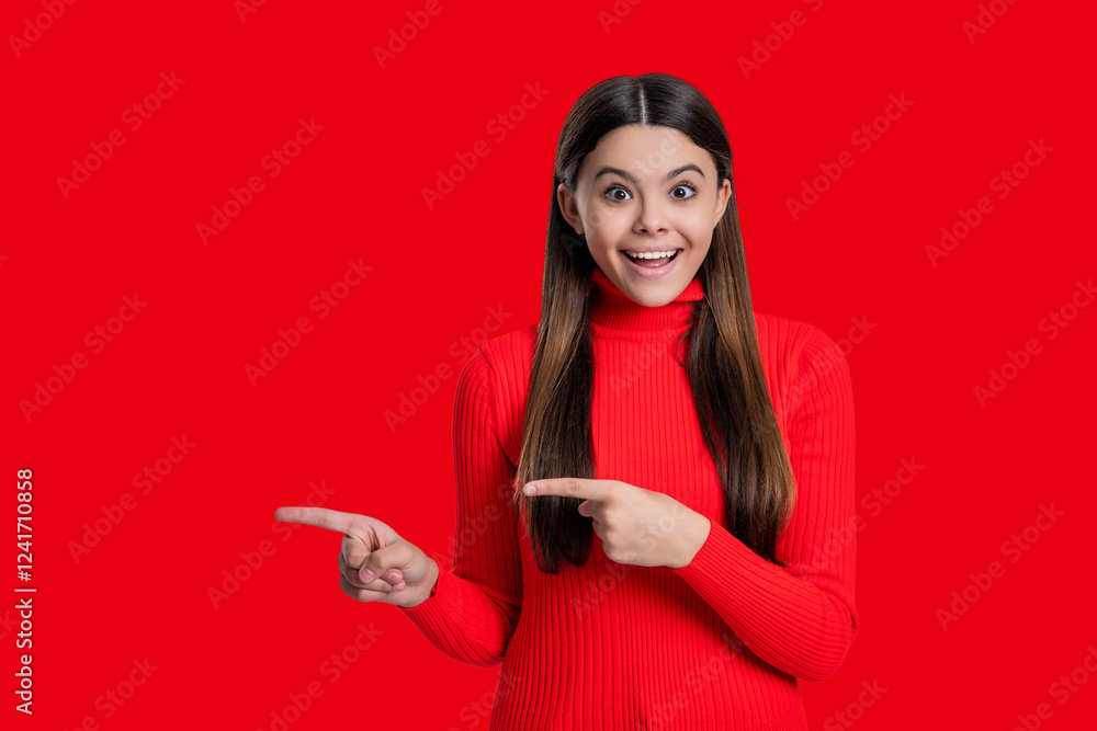 Naklejka premium Teen girl looking at camera. Casual style. Stylish girl has long hair. Teen monochrome fashion style. Style for girl. Headshot portrait of happy teen girl isolated on red. Point finger on copy space