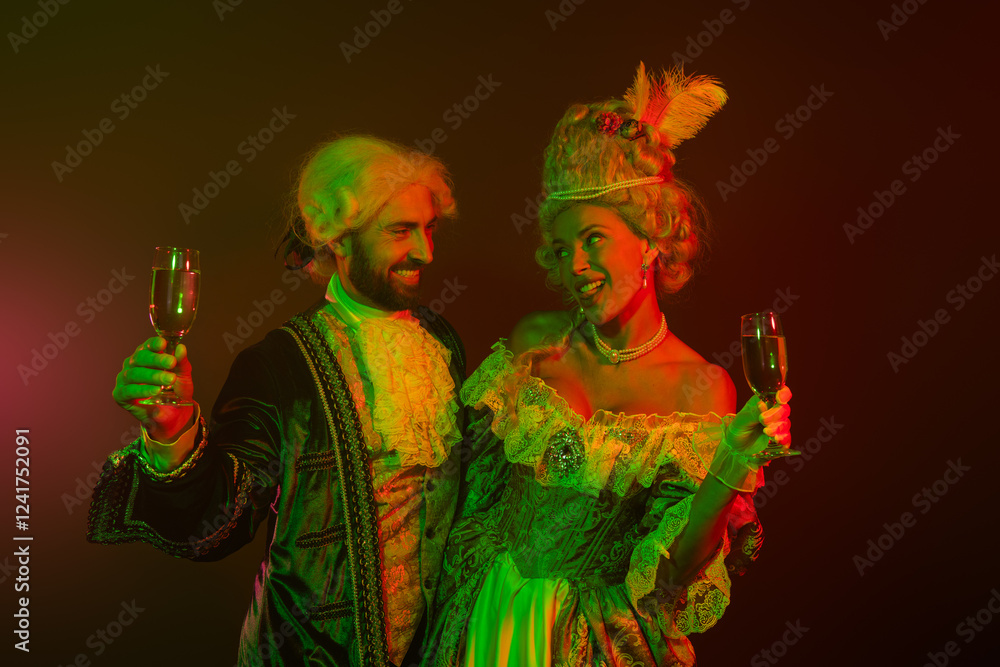 Fototapeta premium Elegant couple dressed in royal vintage costumes enjoying a festive celebration with drinks