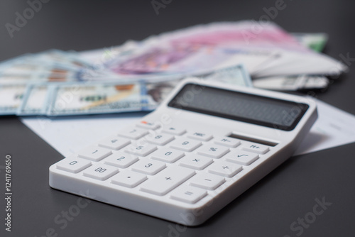 Wallpaper Mural Close-up of a white calculator with money American currency dollars and European currency euros in the background, representing financial calculations. Torontodigital.ca