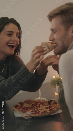 Couple enjoys pizza and wine during a romantic dinner at home.