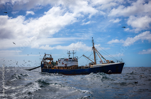 Fishing trawler conducts commercial fishing for fish and seafood in the ocean before the start of storm.