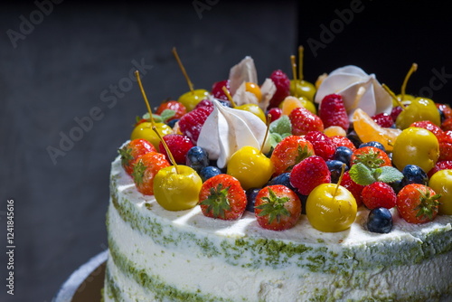 Colorful layer cake with pistachio frosting and fresh fruit toppings.