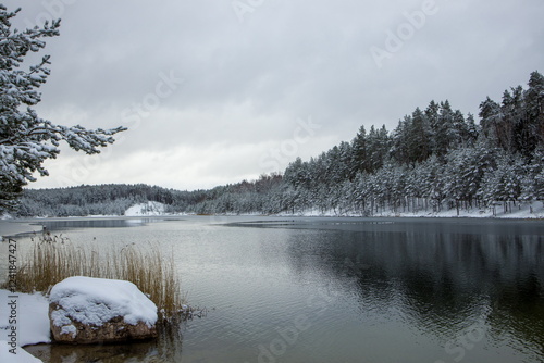 Snow-covered lake surrounded by a winter forest. Dubkalni quarry, Latvia photo