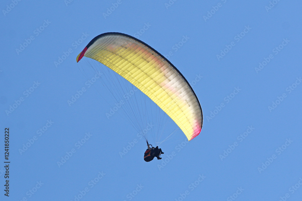Tandem Paraglider flying in a blue sky Tandem Paraglider flying in a blue sky