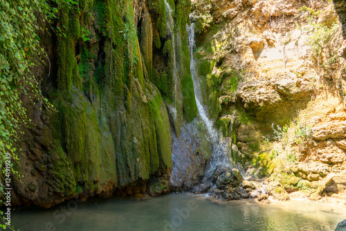 Beautiful view of a waterfall cascading over moss-covered rock walls in the Cuenca region, Spain