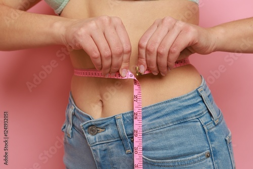 Foto Woman measuring waist circumference on pink background, closeup