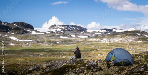 Hiking male sitting outside his tent in a spectacular mountain environment
