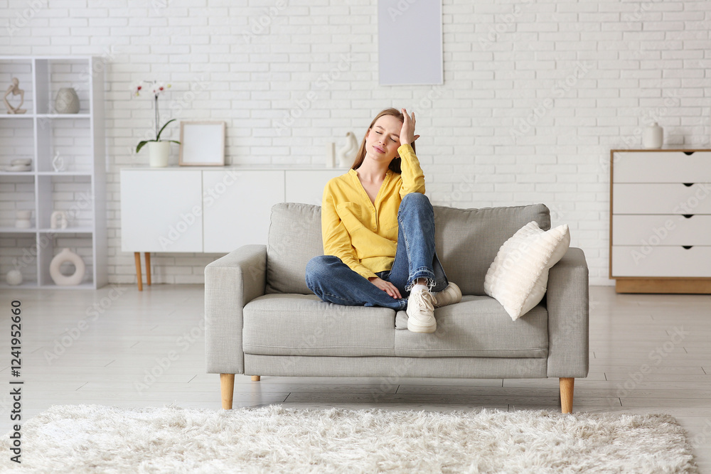 Obraz premium Young woman relaxing on sofa in living room