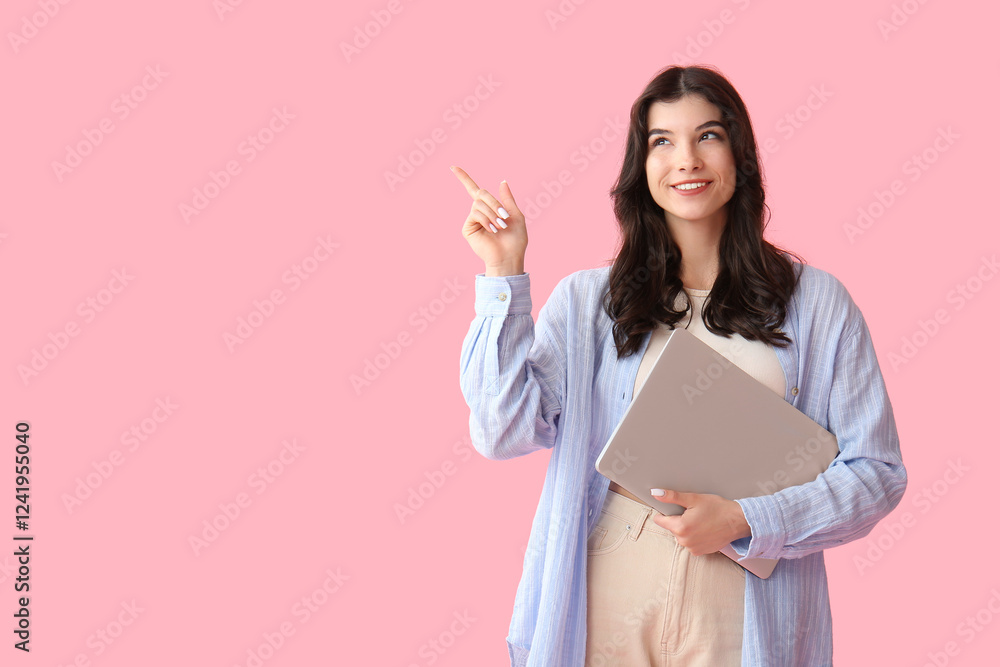 Beautiful young happy woman with laptop pointing at something on pink background Beautiful young happy woman with laptop pointing at something on pink background