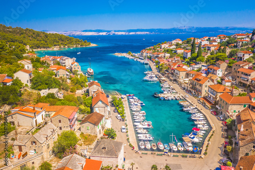 Bild auf Leinwand A picturesque view of Stomorska on Solta Island, Croatia, featuring its scenic harbor, moored boats, and traditional stone houses along the waterfront, creating an inviting summer atmosphere