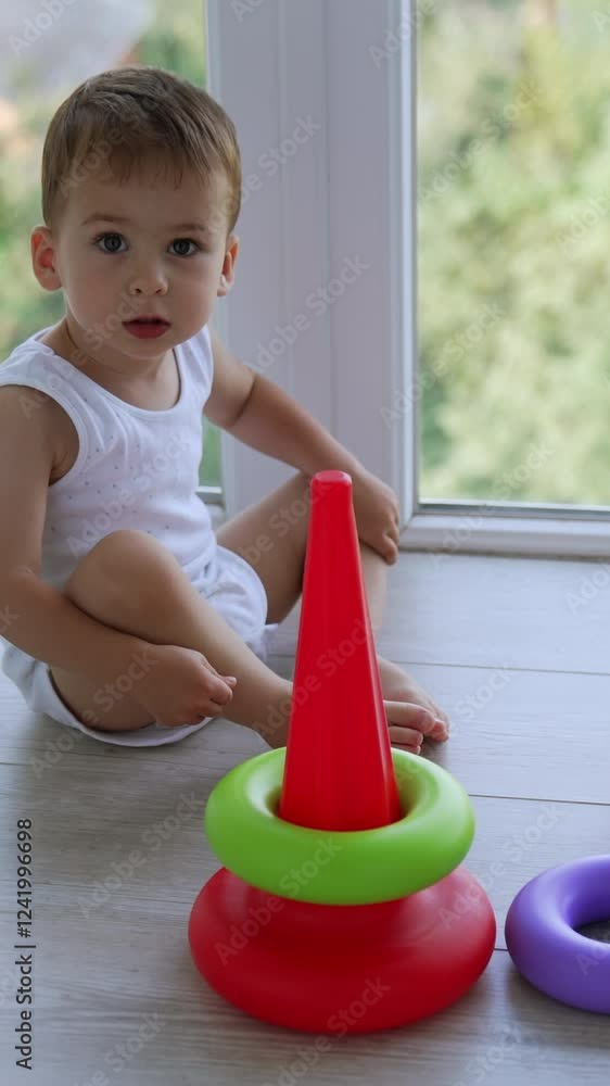 Lovely baby assembling toy pyramid. Caucasian boy plays at home near the window. Vertical video Lovely baby assembling toy pyramid. Caucasian boy plays at home near the window. Vertical video