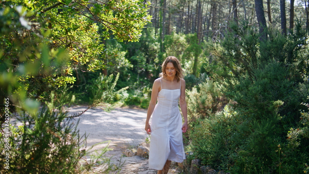 Serene woman walking garden in dress. Carefree girl stepping pathway nature Serene woman walking garden in dress. Carefree girl stepping pathway nature