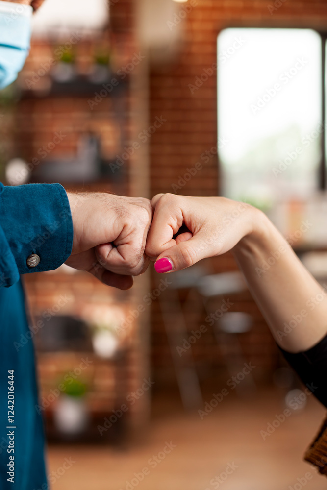 Obraz premium Business partners in office share fist bump, symbolizing teamwork and mutual support. Caucasian coworkers doing hand gestures that highlights strong partnership in startup company.