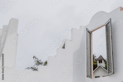 White Stair-Step Architecture with Wooden Louvered Shutters framing pitched roof bell tower photo