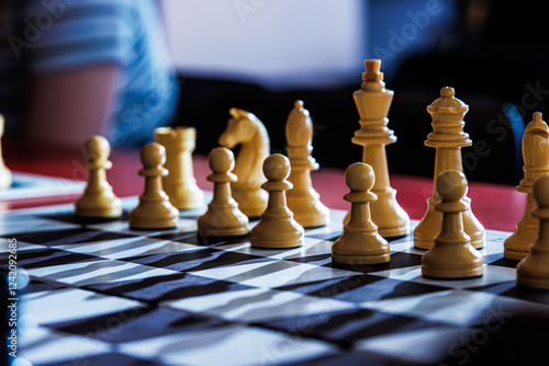 Closeup of a chessboard with a white pieces arranged for a match, symbolizing  competition, decision making, strategic thinking, and mental challenge.  Chess game in progress. Selective focus 
 photo