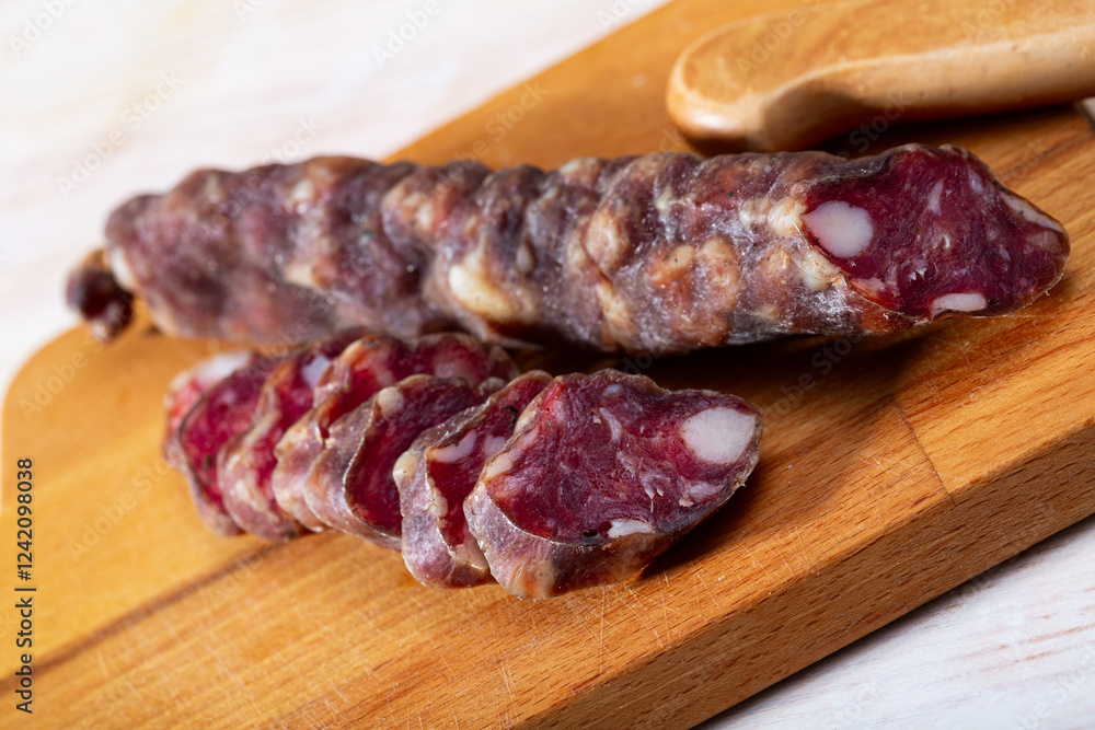Sliced French dry sausage on wooden cutting board Sliced French dry sausage on wooden cutting board