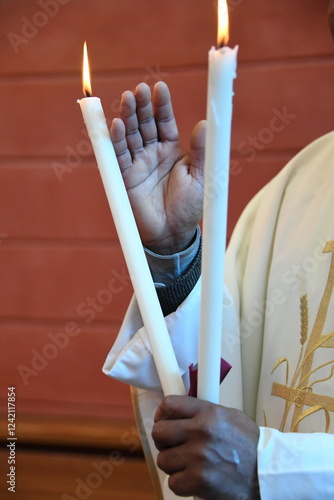 Ein römisch-katholischer Pfarrer erteilt den Blasiussegen. Dabei werden brennende Kerzen gerkreuzt. Der Priester spricht ein Gebet und bitte um die Fürsprache des Heiligen Hl. Blasius 