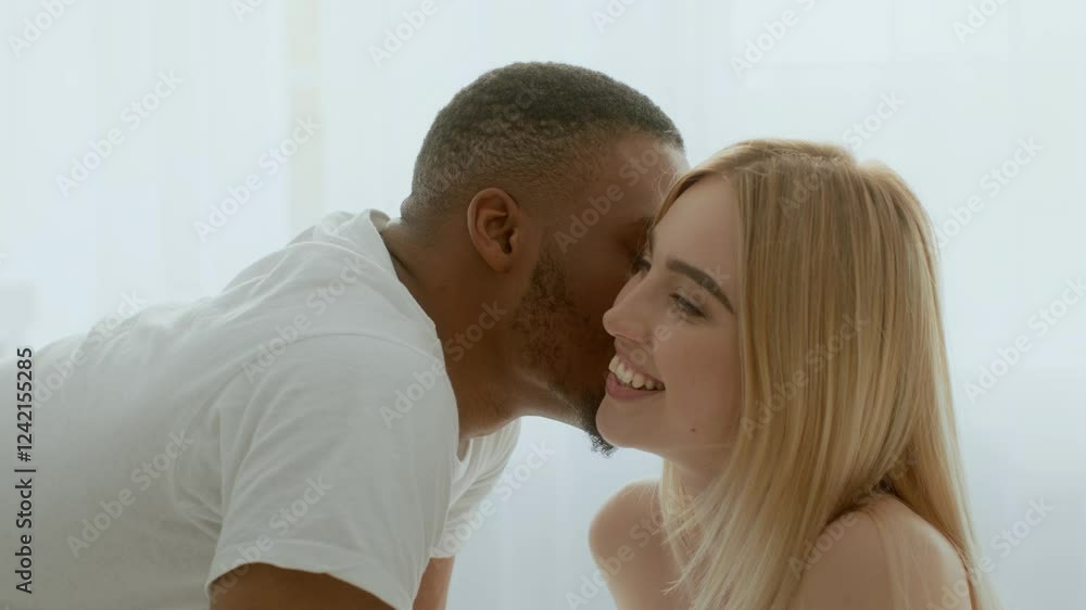 A young multiracial couple enjoys a moment of intimacy in their cozy bedroom. Their laughter and smiles reflect their deep connection and affection for each other. A young multiracial couple enjoys a moment of intimacy in their cozy bedroom. Their laughter and smiles reflect their deep connection and affection for each other.