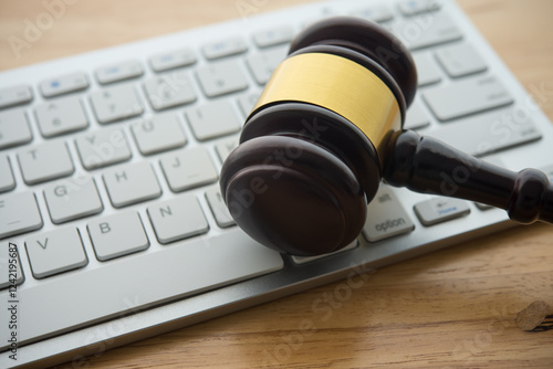Foto Judge hammer gavel on computer keyboard wooden table background