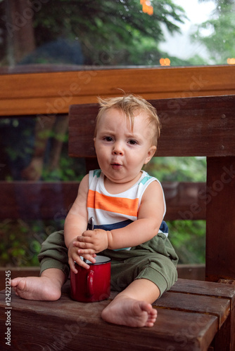 Baby Sitting with Red Mug in Nature and Singing photo