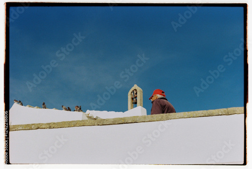 Unidentified man against a blue sky and white wall photo