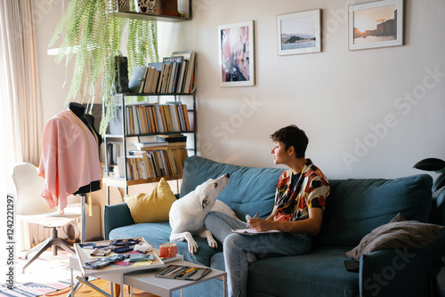 Designer and dog looking at each other during woman drawing on paper photo