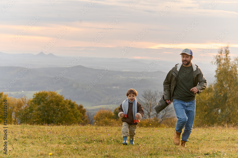 Dad and son walking in a mountain meadow at sunset Dad and son walking in a mountain meadow at sunset
