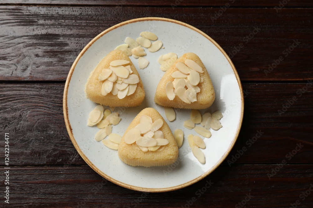 Pieces of delicious semolina halva with almond flakes on wooden table, top view Pieces of delicious semolina halva with almond flakes on wooden table, top view