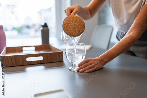 Woman pouring refreshing water into glass in coworking space photo