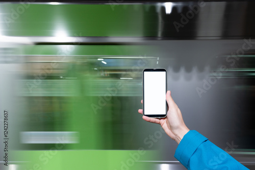 Woman hand holding phone in front of subway in motion photo