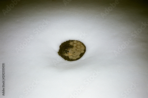 Hot manhole appearing in the middle  of snow cover street 