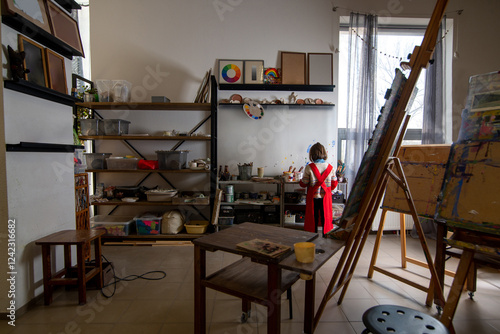 Little child in apron in large classroom-workshop in art school photo