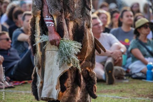 Human hands hold wooden dish with Australian plant branches, the smoke ritual rite at a indigenous community event in Australia