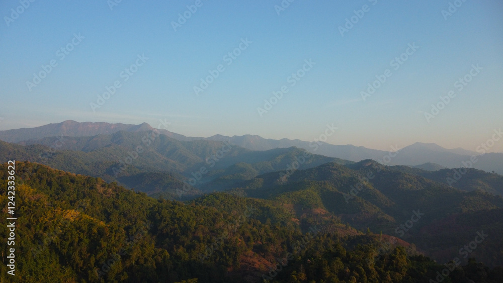 Beautiful sunrise on the mountain with fog in winter. The sun shines down on a serene mountain landscape covered with tropical trees in the early morning. Beautiful sunrise on the mountain with fog in winter. The sun shines down on a serene mountain landscape covered with tropical trees in the early morning.