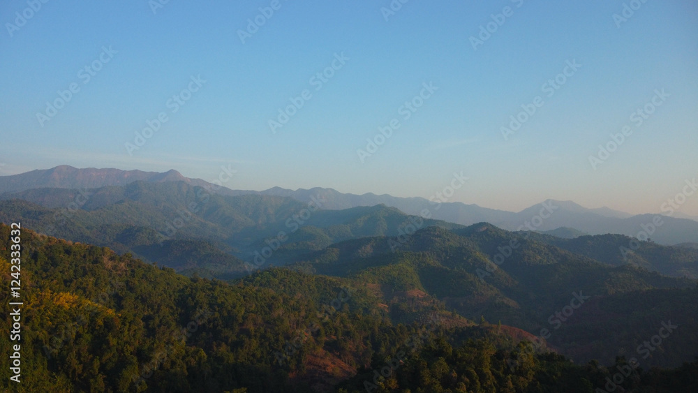 Beautiful sunrise on the mountain with fog in winter. The sun shines down on a serene mountain landscape covered with tropical trees in the early morning. Beautiful sunrise on the mountain with fog in winter. The sun shines down on a serene mountain landscape covered with tropical trees in the early morning.
