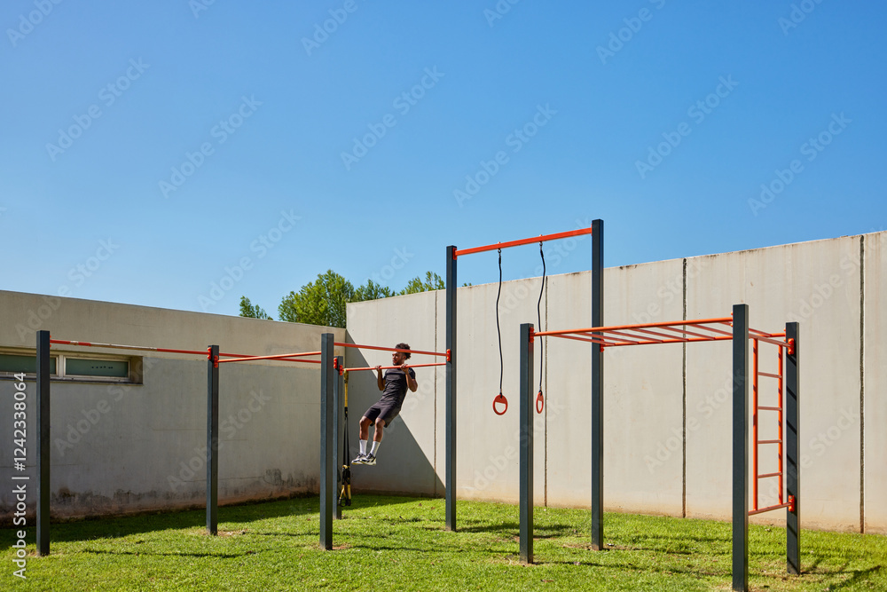 Athletic man hanging on exercise bar on sunny day Athletic man hanging on exercise bar on sunny day