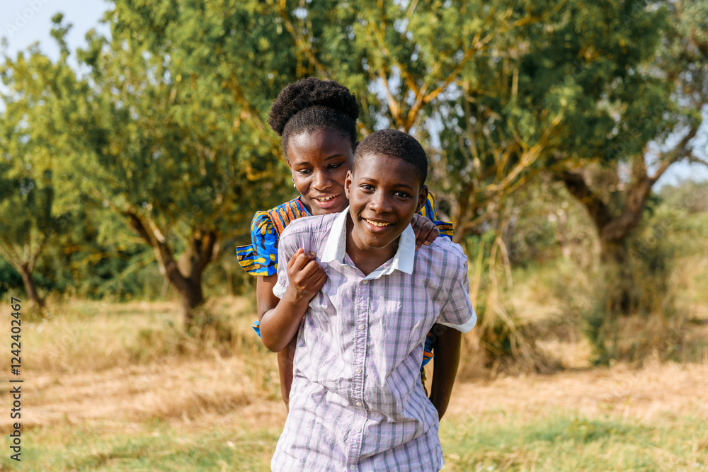 Happy senegalese sibling carrying sister on his back in field Happy senegalese sibling carrying sister on his back in field
