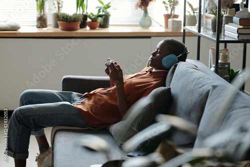 Gen Z Girl Resting on Couch with Headphones and Smartphone photo